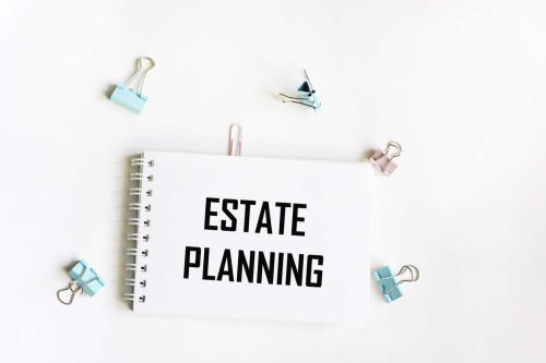 A notebook with the text Real estate planning. Paper clips on a white background. Business concept