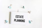 A notebook with the text Real estate planning. Paper clips on a white background. Business concept